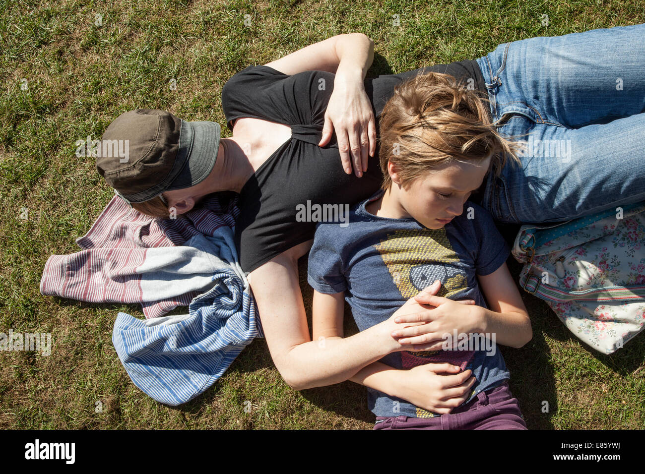 A mother and her boy sleeping together on grass Stock Photo