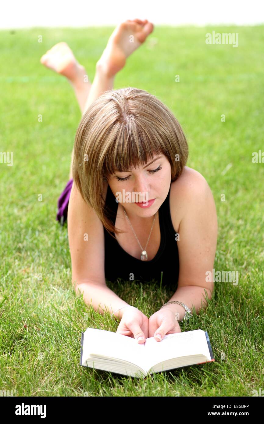 Young beautiful girl reading in the park laying on the grass Stock ...