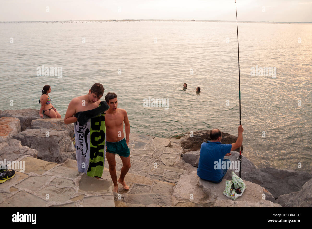 People swim and fish in Adriatic Sea at village of Duino Trieste Italy Stock Photo