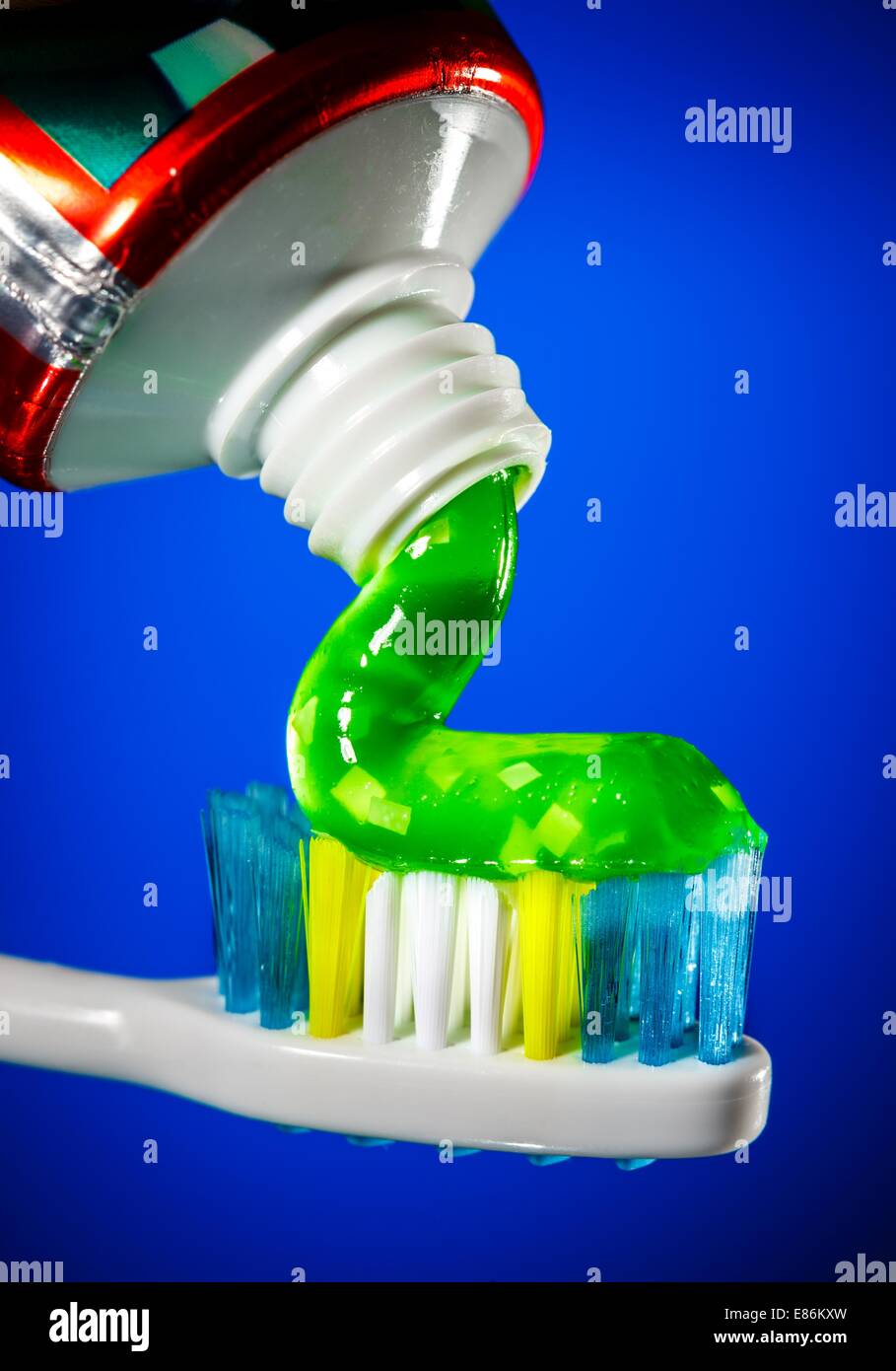 Toothpaste being squeezed onto a toothbrush on a blue background Stock ...