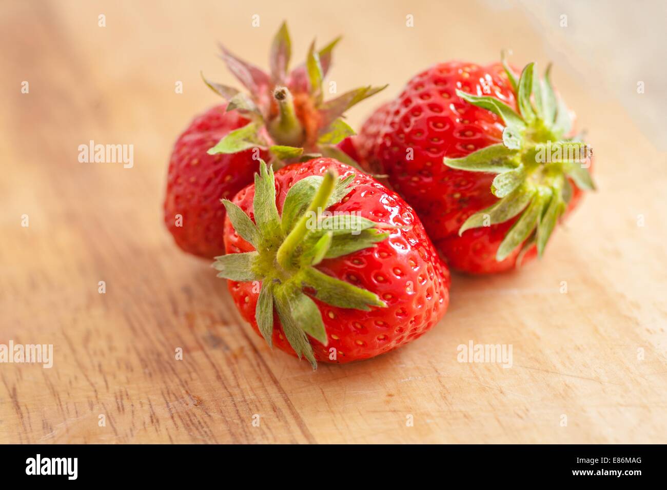 three strawberries on wooden table Stock Photo - Alamy