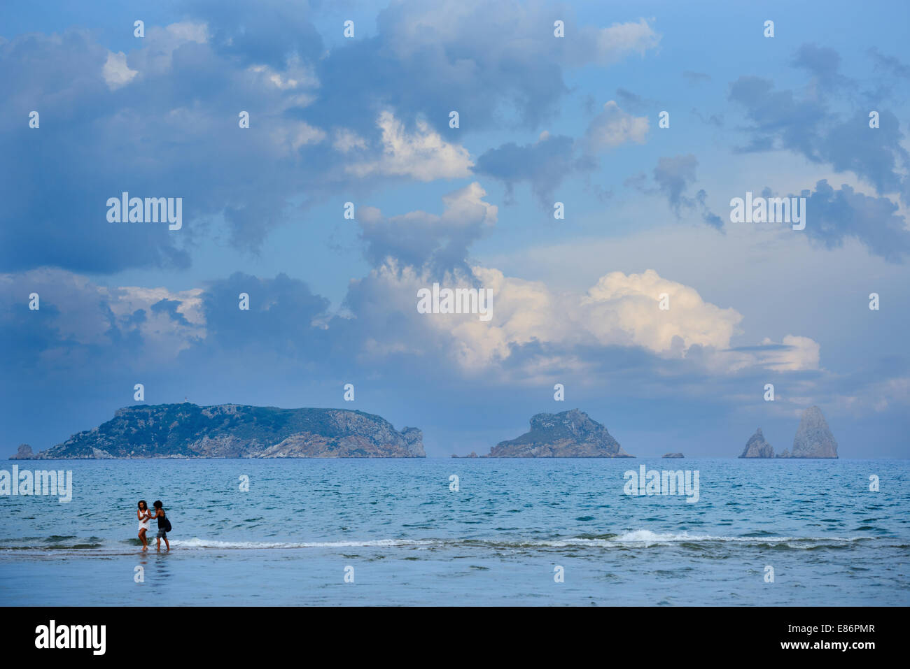 Two young women walk on the shores of the Mediterranean, in front of the Illes Medes natural park and reserve. Stock Photo