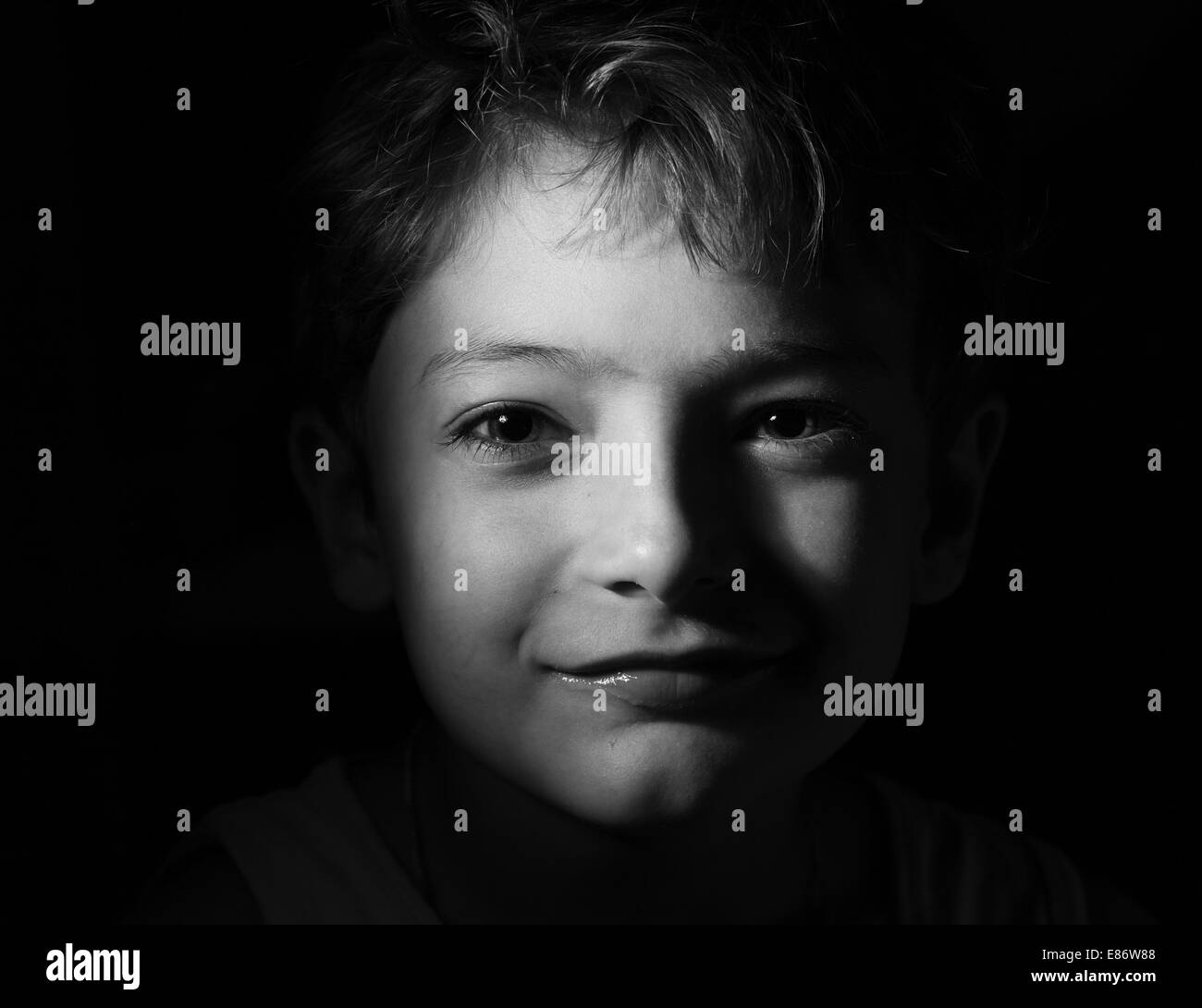 black and white shot of the boy in the dark, focused light on the head ...