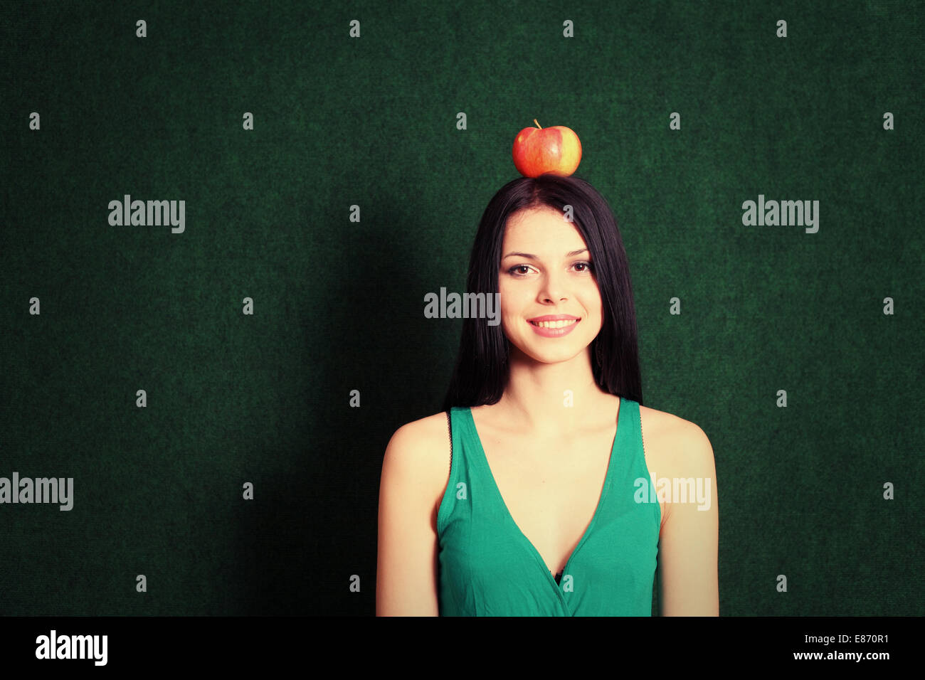 front view of the young female with an apple on her head and a lot of copyspace Stock Photo