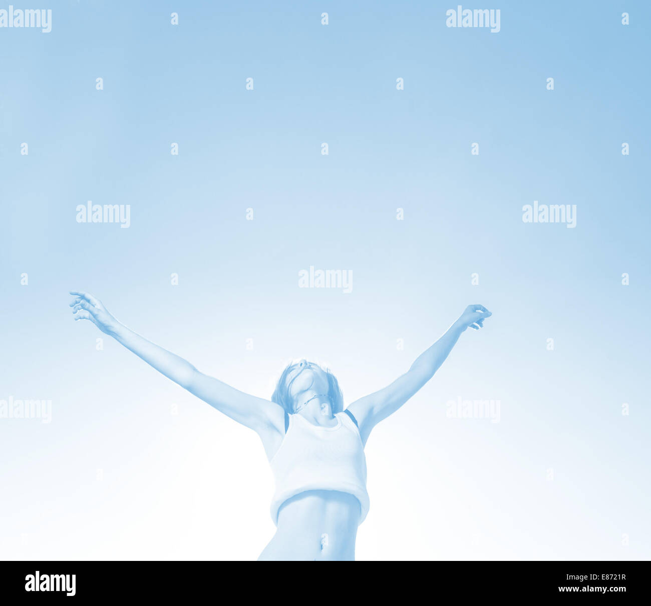 Toned in blue Blonde teenager girl jumping happy with the blue sky in ...