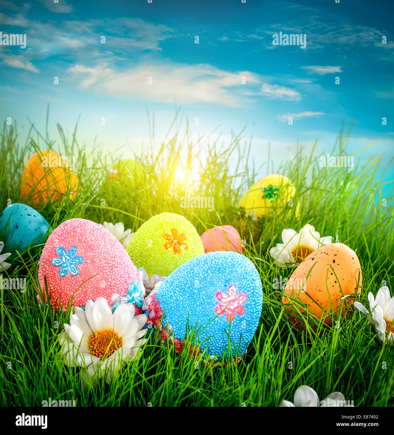 Decorated easter eggs in the grass on blue sky background Stock Photo ...