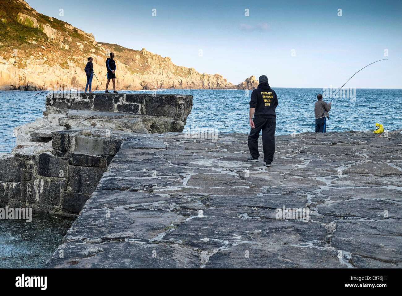 Anglers fishing off the remains of the neglected and damaged quay at Lamorna Cove in Cornwall. Stock Photo