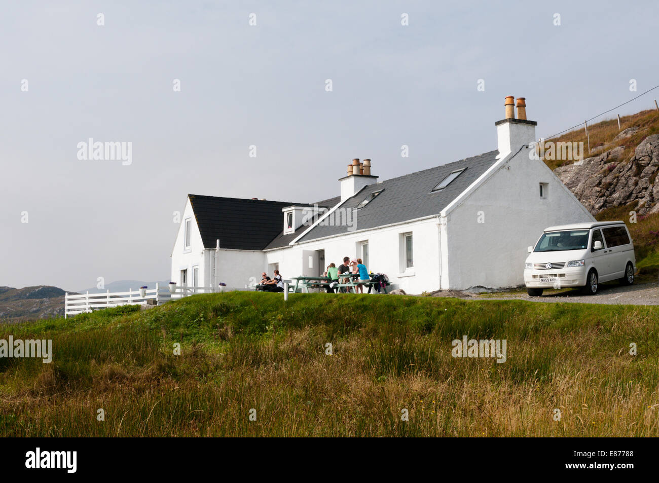 People sitting outside the Skoon Art Cafe at Geocrab on South Harris in the Outer Hebrides. Stock Photo
