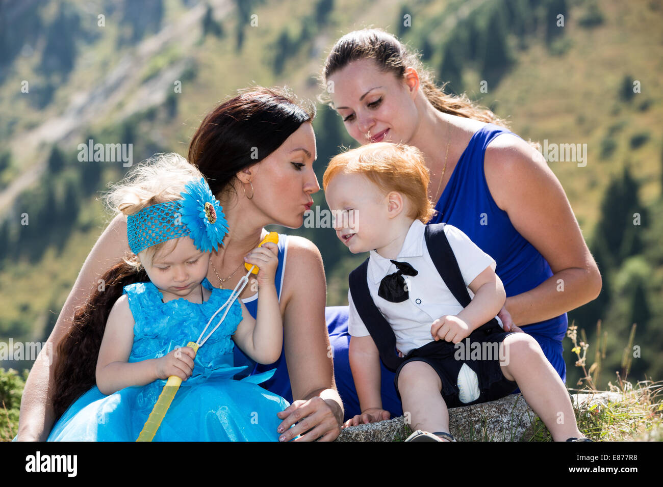 Two happy moms and children girl and boy hugging on nature The concept of childhood and family. Stock Photo