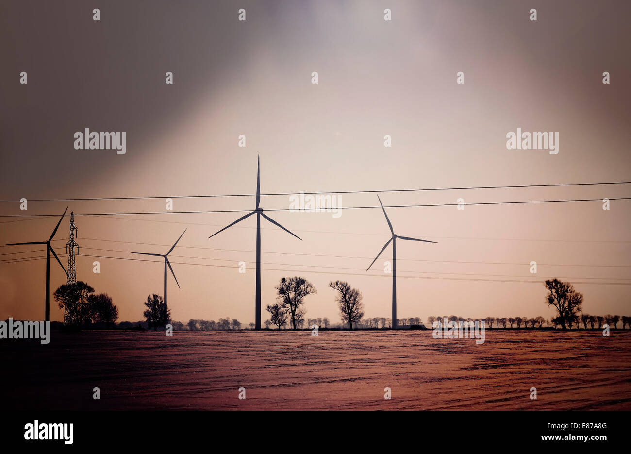 Retro dark abstract picture of wind turbines on field. Stock Photo