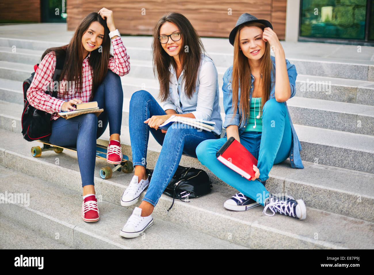 Portrait of happy teen girls looking at camera on stairs of college Stock Photo