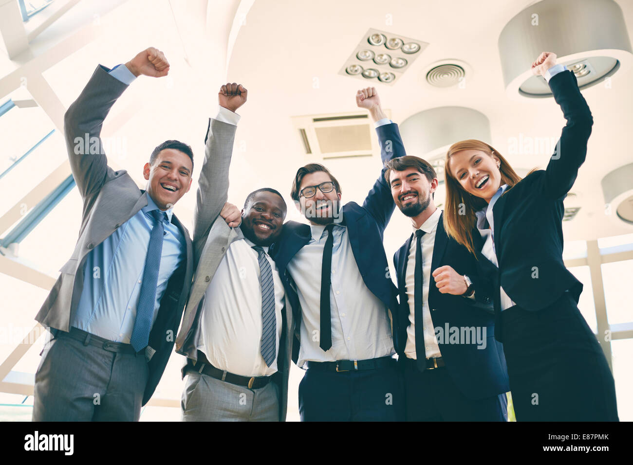 Group of ecstatic business leaders with raised arms expressing their gladness Stock Photo