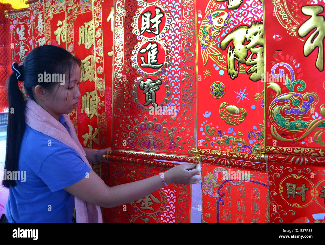 Woman hanging up Chinese New Year Festival couplets in outdoor market Stock Photo