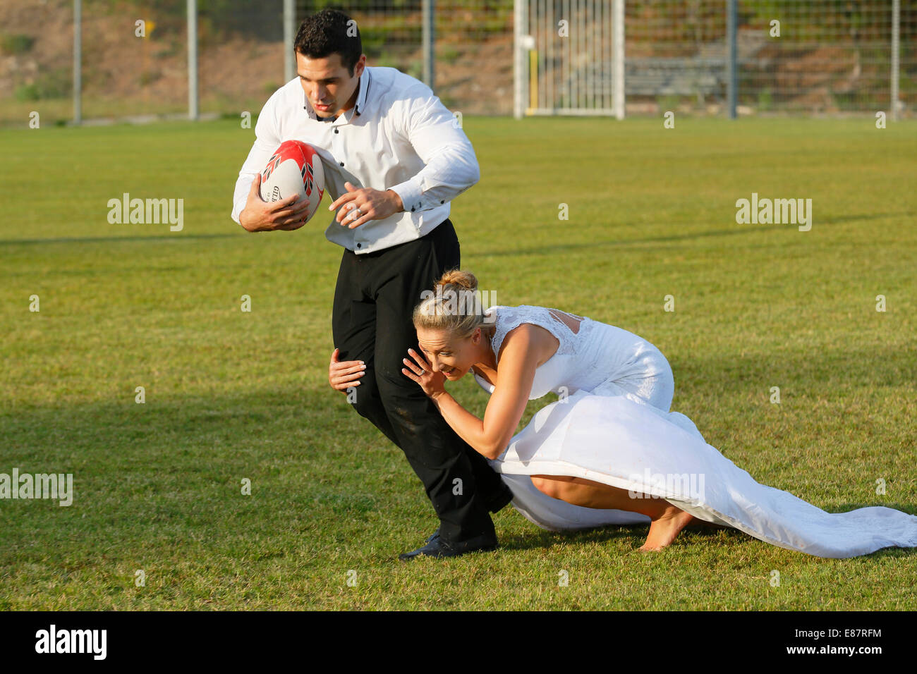 Trash the dress, bride and groom playing rugby, bride tackling the groom Stock Photo