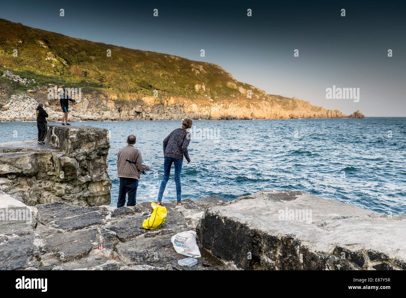 People fishing off the damaged quay at Lamorna Cove in Cornwall. Stock Photo