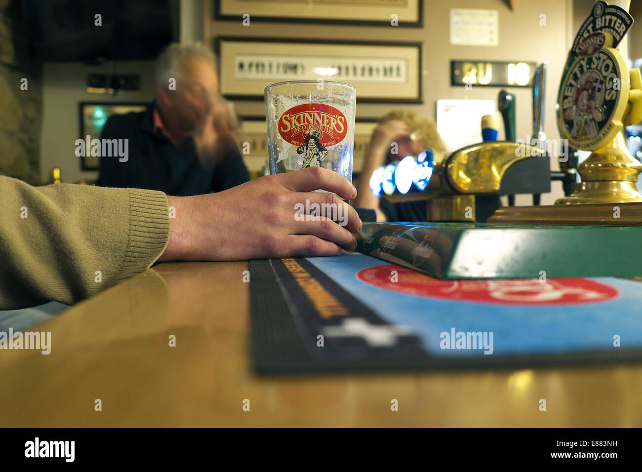 A man holding a partially consumed pint of Skinner's Ale in The Wink pub at Lamorna in Cornwall. Stock Photo