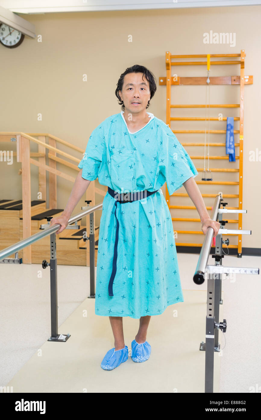 Male Patient Standing With The Support Of Bars Stock Photo