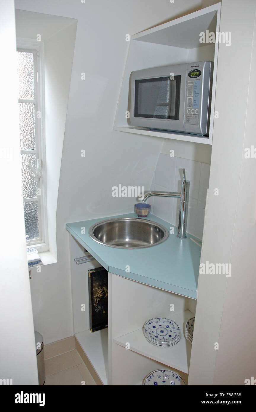 Microwave oven on shelf above built in stainless steel sink in small