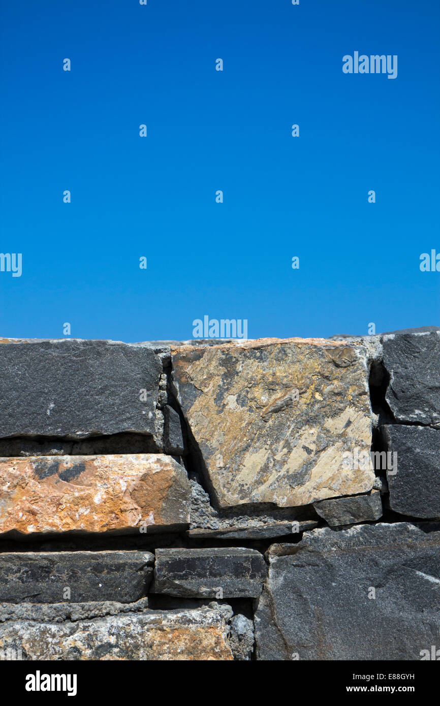 Stone wall detail with blue sky in background Stock Photo