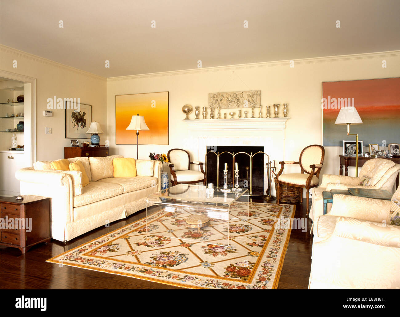 Cream sofas on either side of large floral patterned rug on floor of modern living room Stock Photo