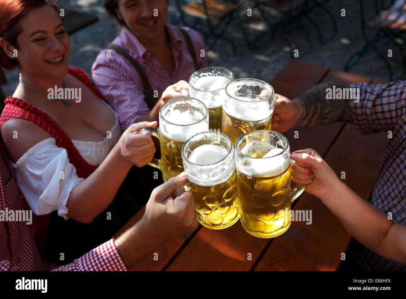People in traditional costumes drinking beer in a Bavarian beer garden Stock Photo