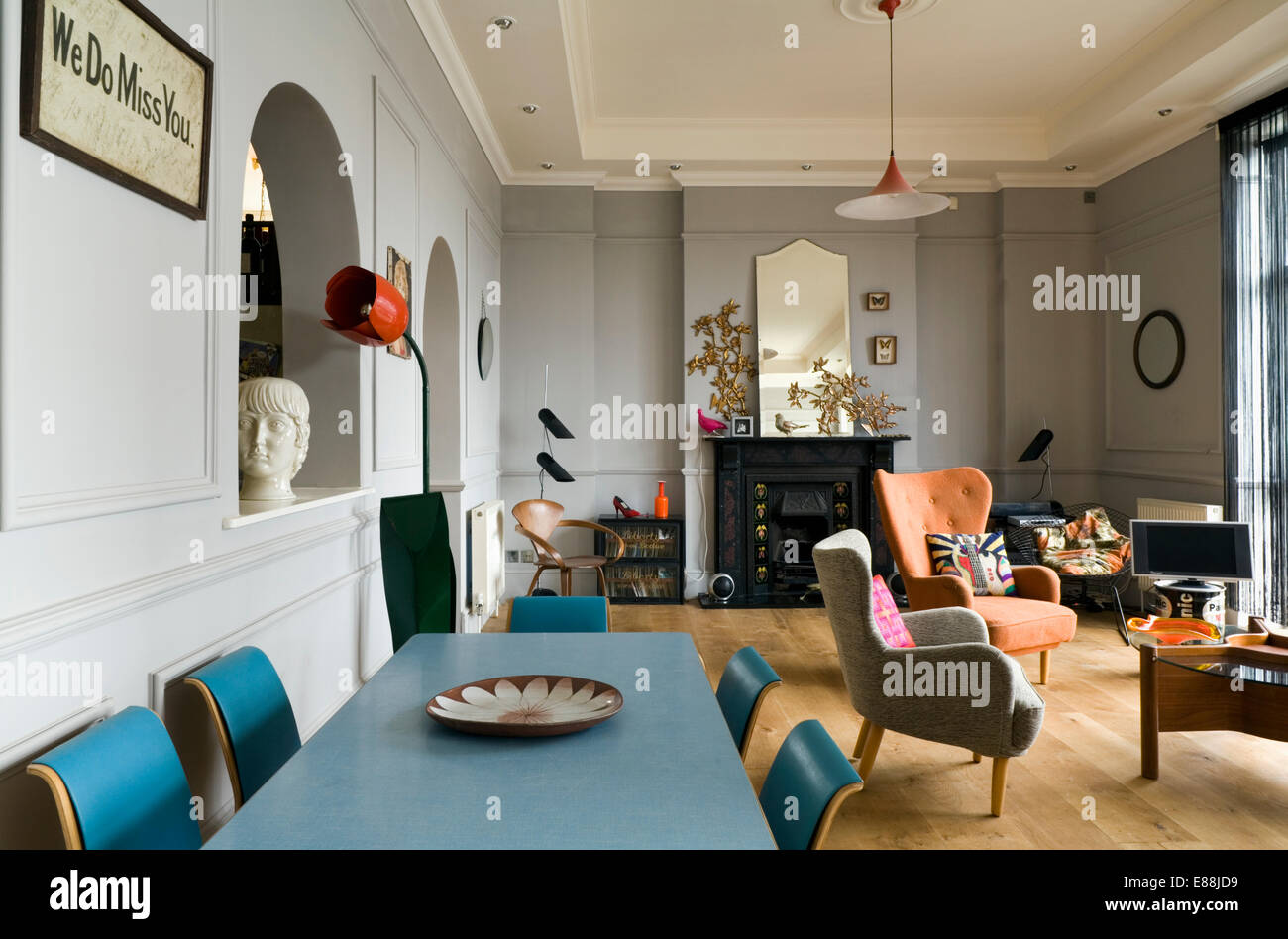 Blue fifties dining table and chairs in pale grey living room with fifties armchairs and sofa Stock Photo