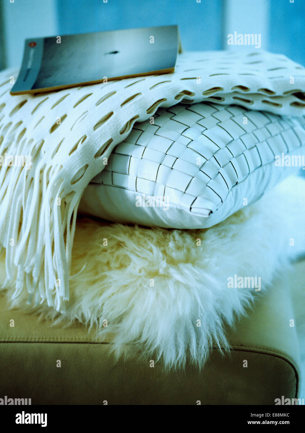 Close-up of a pile of  faux and woven silk cushions with cut-wrok white fleece throw Stock Photo