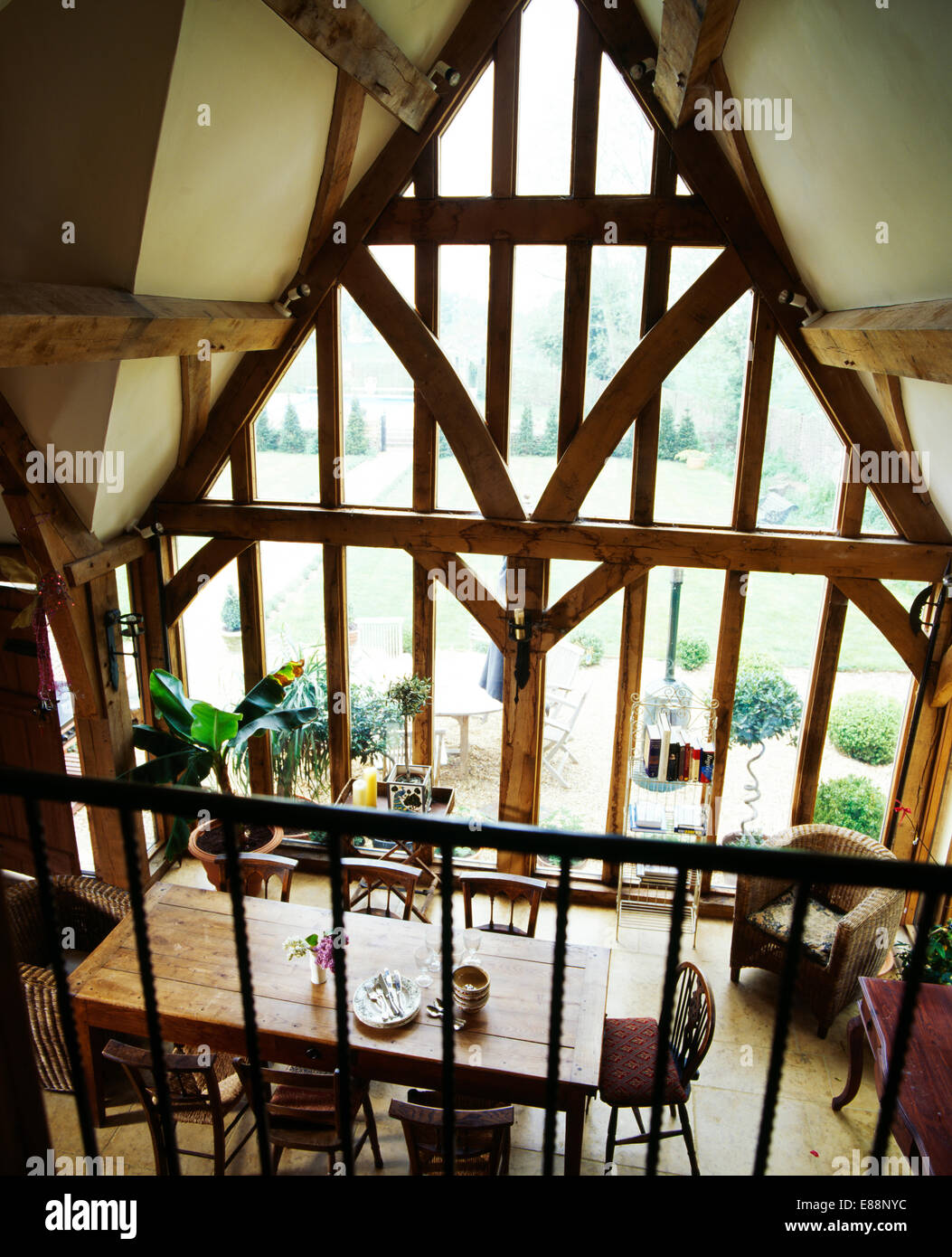 Birdseye view of antique wooden table in barn conversion dining room with large floor-to-ceiling apex window Stock Photo