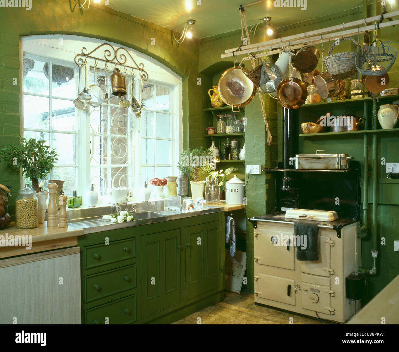 Batterie-de-Cuisine above cream Aga oven in traditional green kitchen Stock Photo