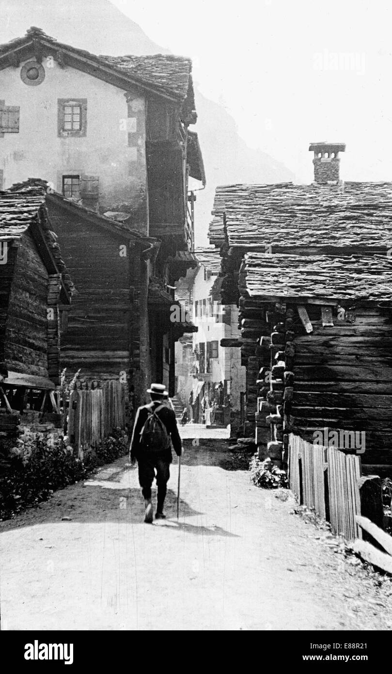 Walker passing through Evolène, Valais, Switzerland. July 1911. Reproduced from a glass lantern slide. Stock Photo