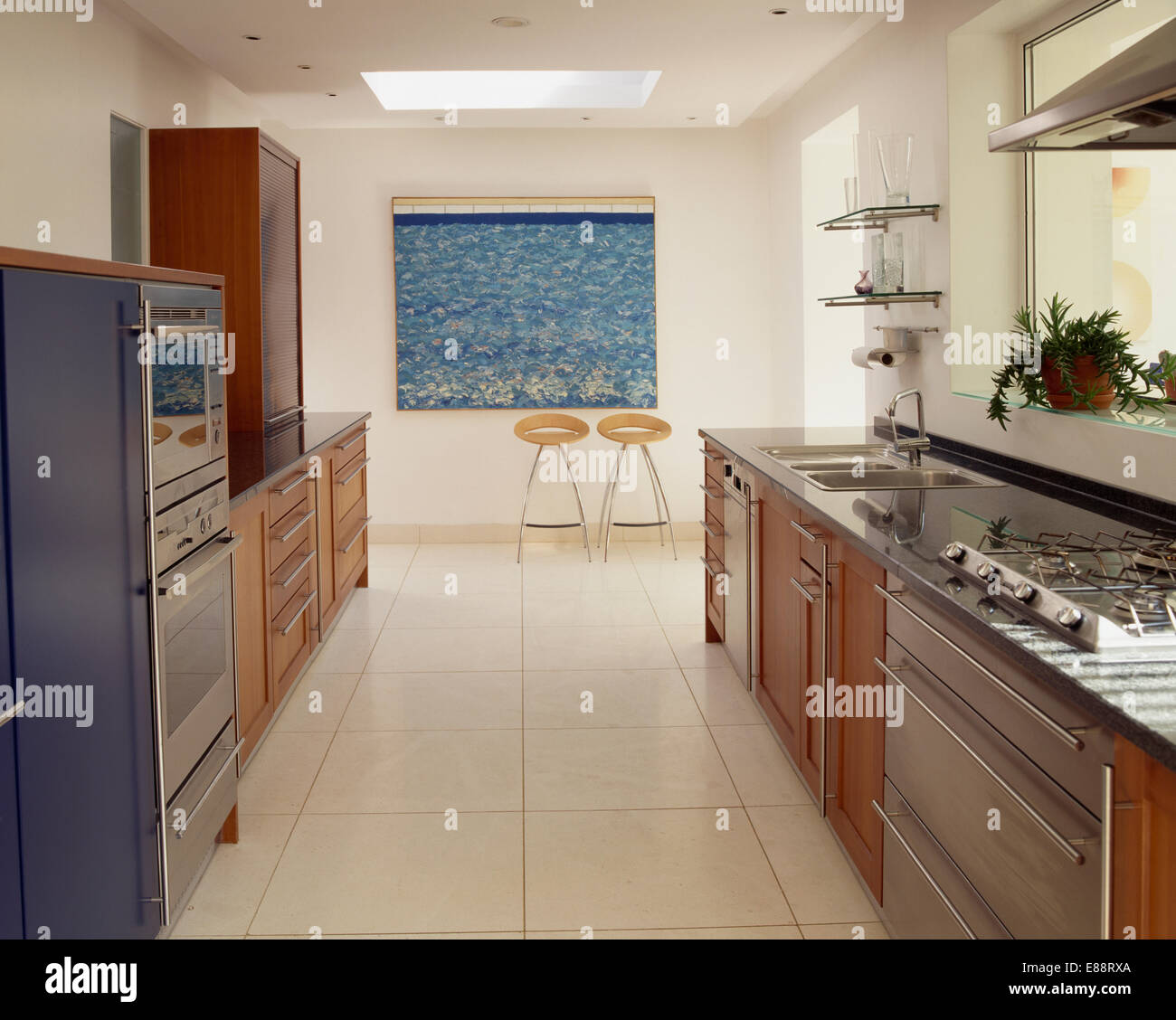 Cream Travertine flooring in large modern galley kitchen with hob set in fitted unit Stock Photo