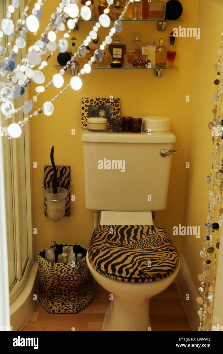 Animal-print seat on toilet in small bathroom with animal-print waste-bin Stock Photo