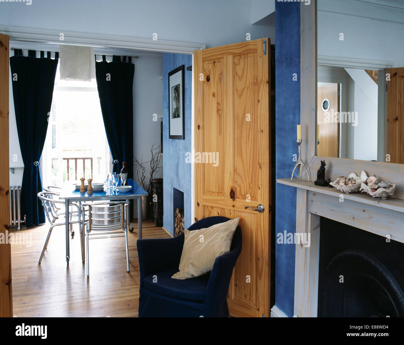 Townhouse living room with stripped pine door open to modern dining room Stock Photo