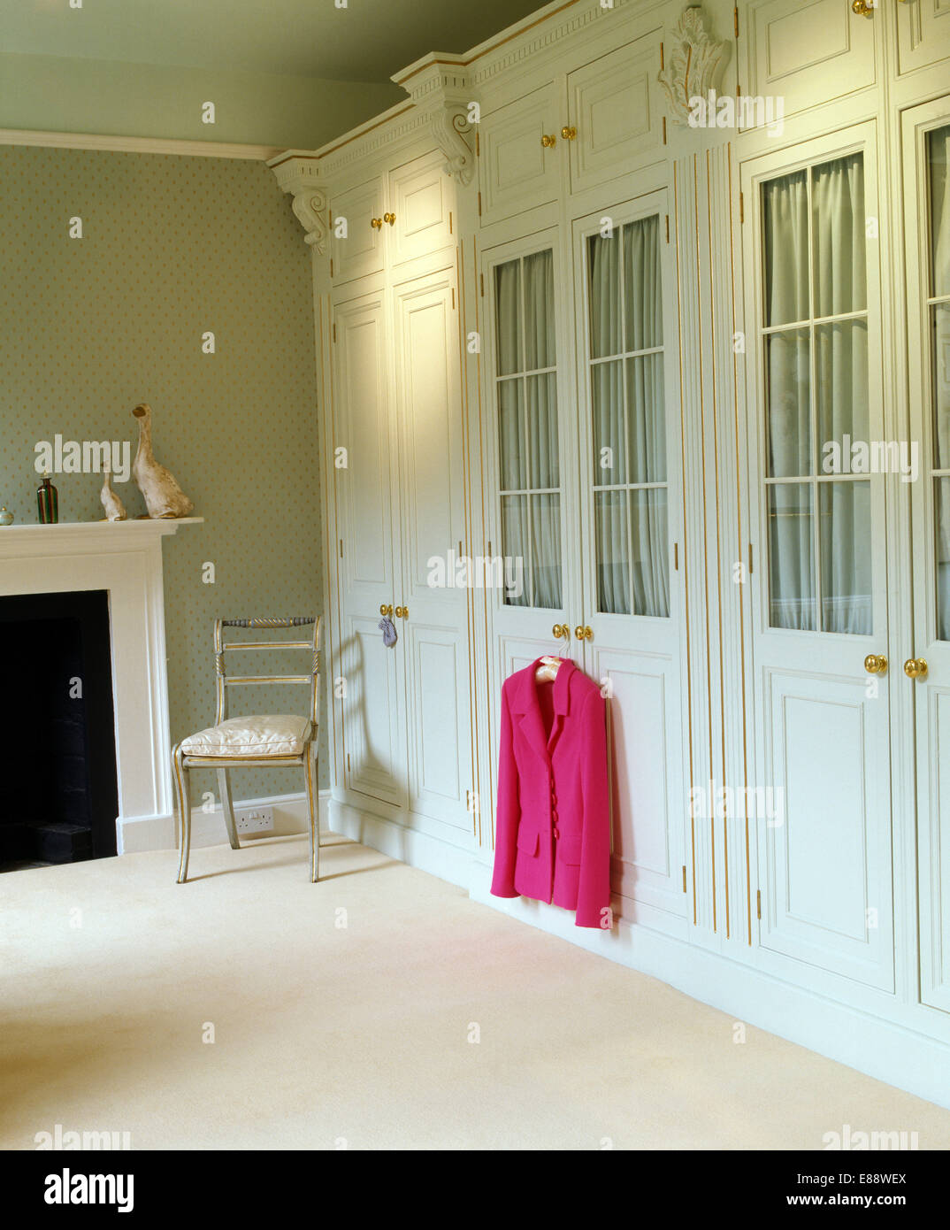 Pink Jacket Hanging On Fitted Wardrobe With Half Glazed Doors In