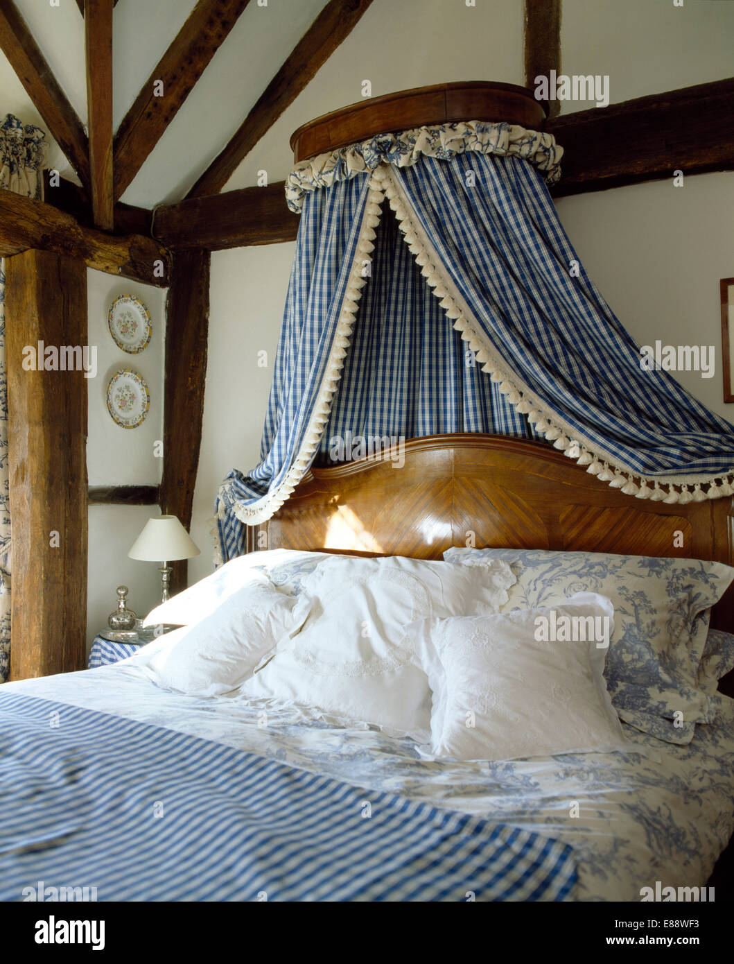 with checked drapes above antique bed with white cushions and blue+white floral bedlinen