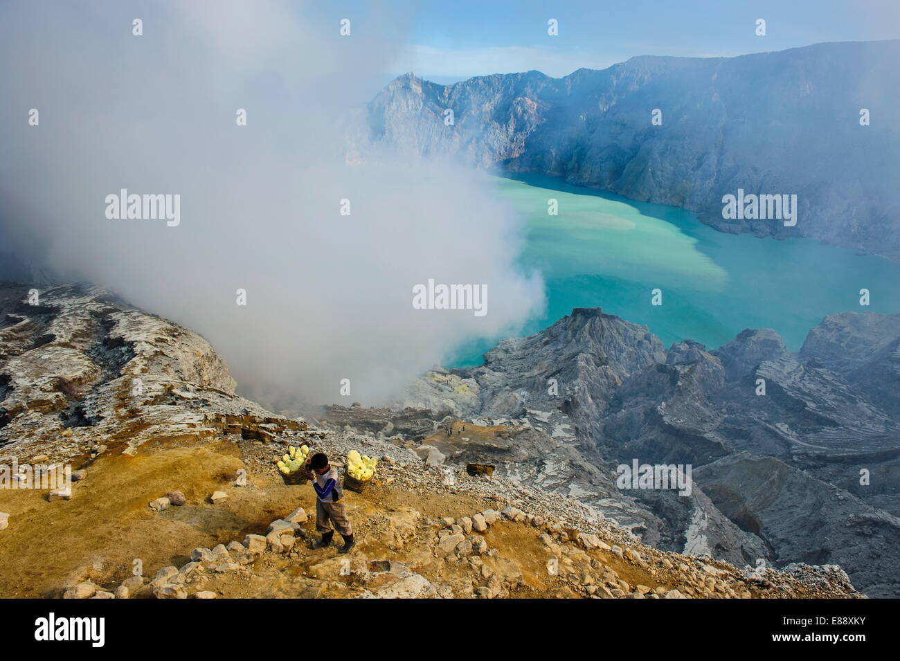 Worker loaded with big pieces of sulphur in front of steam clouds on the Ijen crater lake, Java, Indonesia, Southeast Asia, Asia Stock Photo