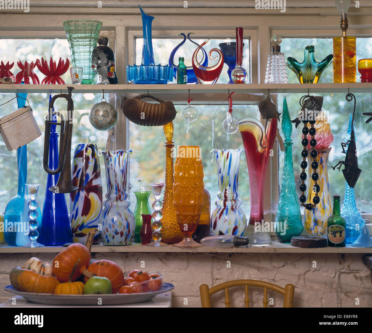 Collection of colourful glass bottles and vases on window shelves Stock Photo