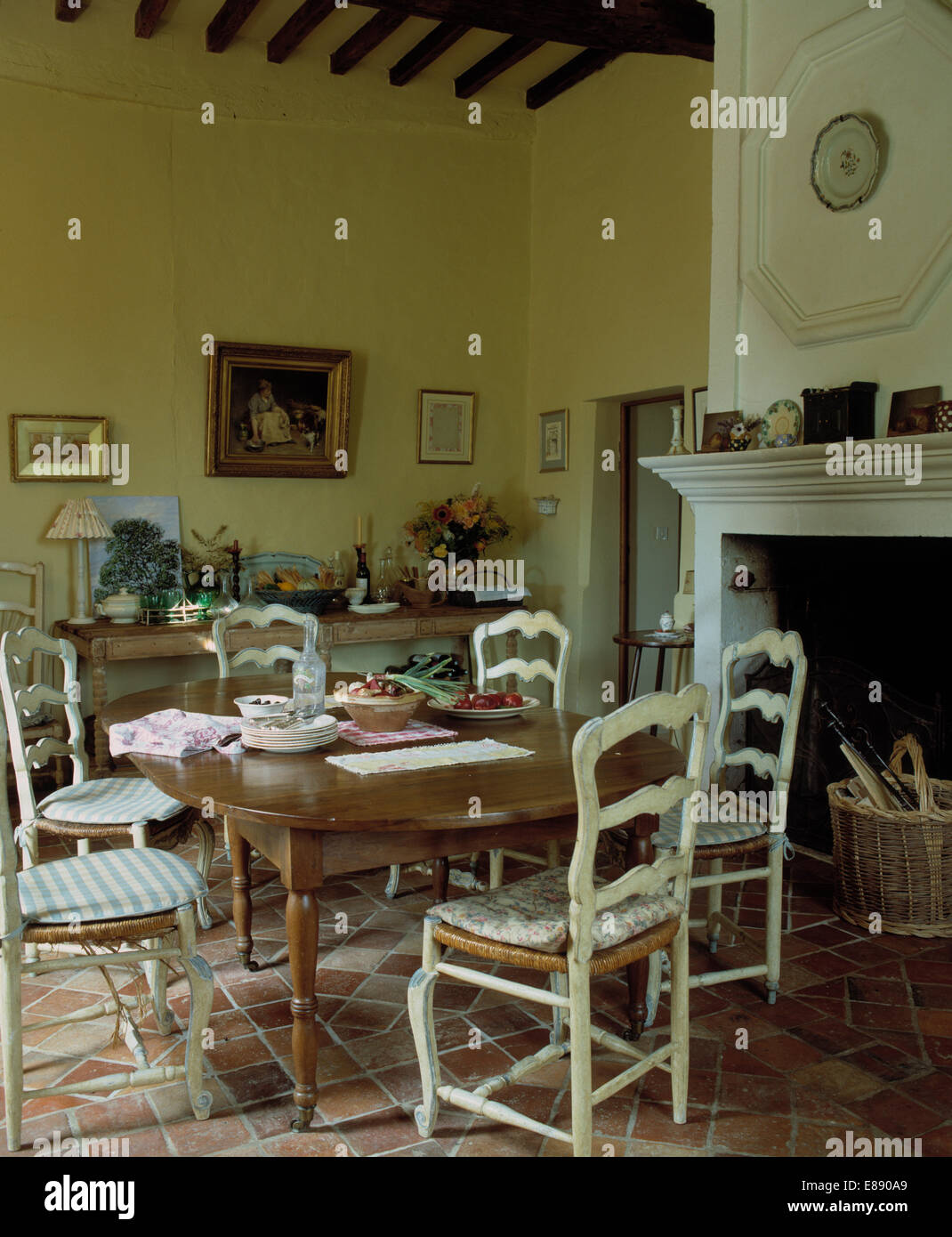 Antique table with painted ladderback chairs with cushions on rush seats in traditional French