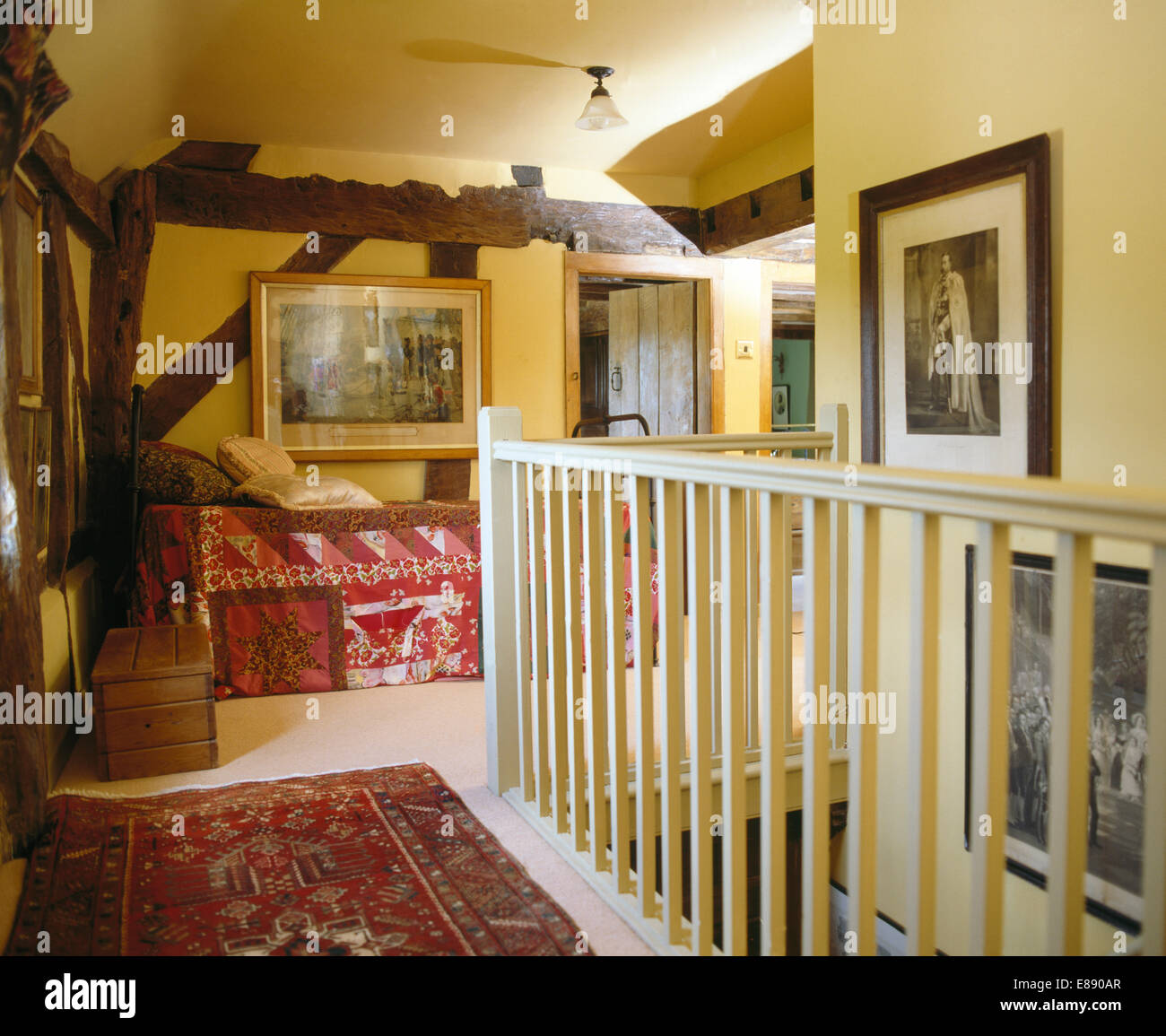 White painted banisters on landing with old oriental rug and day bed