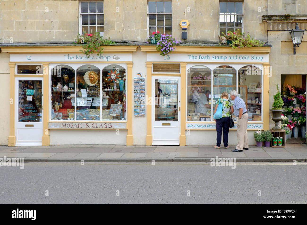 A man and a woman look at the window display of the Bath stamp and coin shop on Pulteney Bridge in Bath,Somerset,UK. Stock Photo