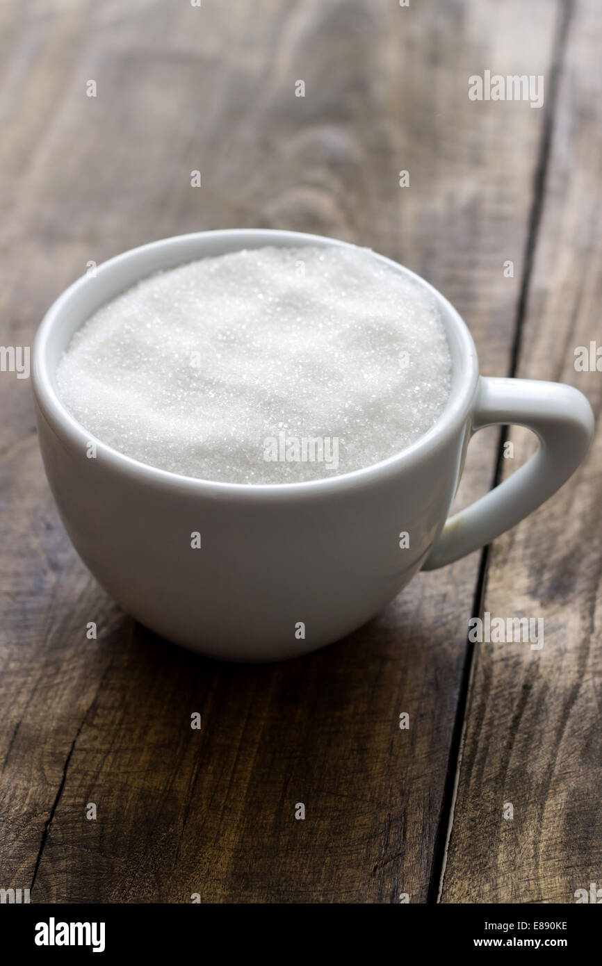 A cup of sugar on retro wooden background Stock Photo - Alamy