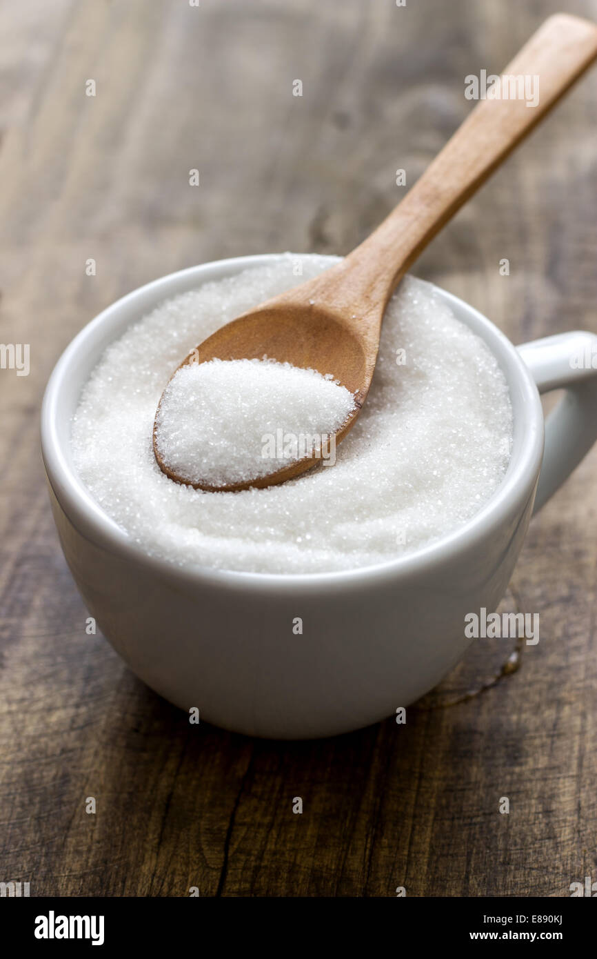 A cup of sugar on retro wooden background Stock Photo - Alamy