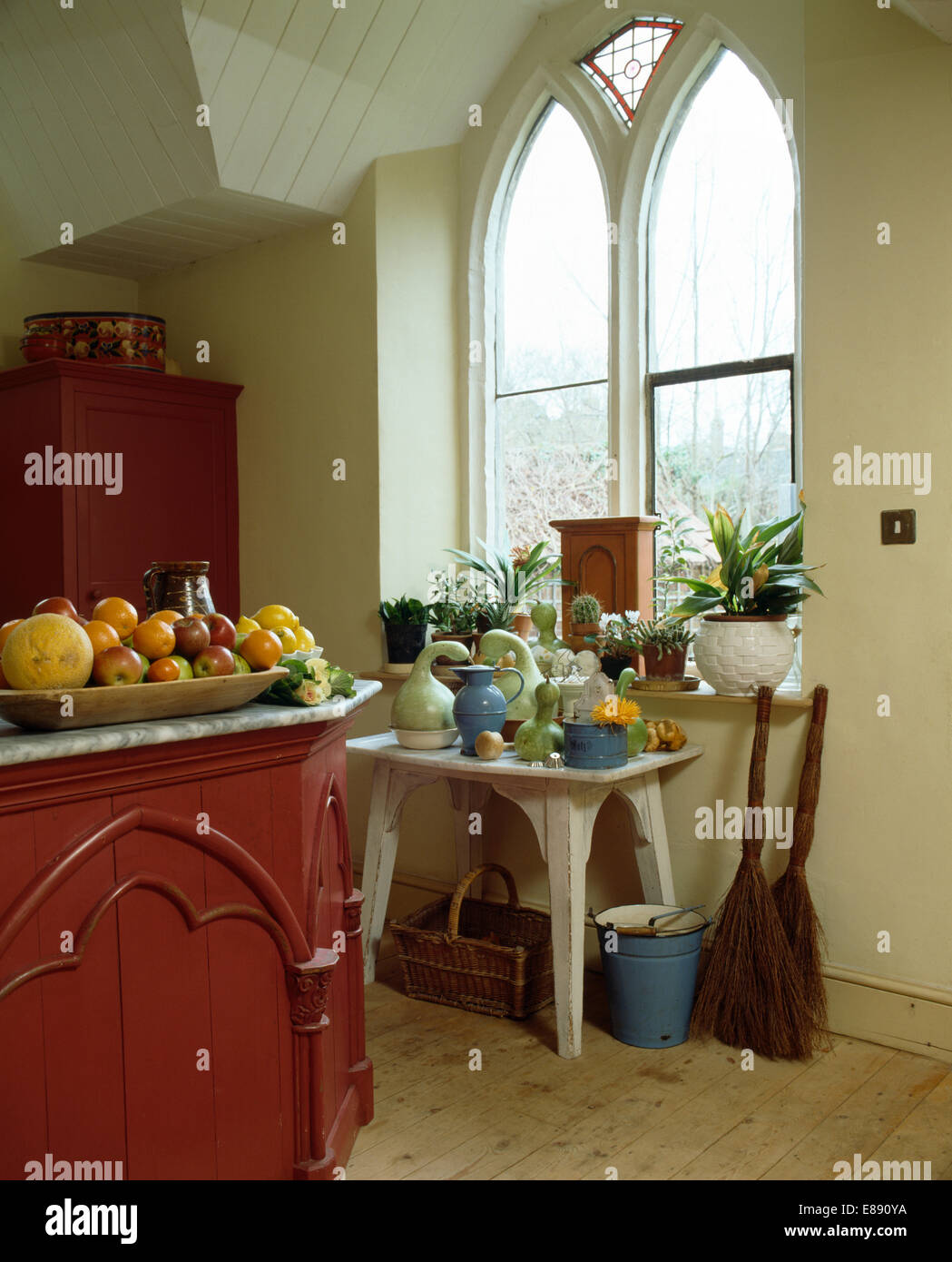 Small table below Gothic-style window in kitchen of converted church ...