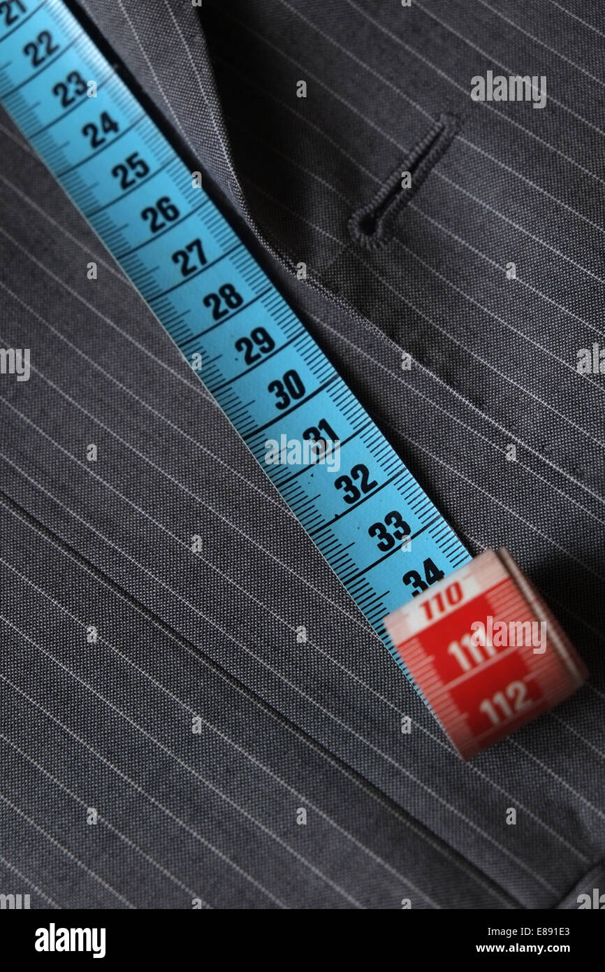 Measure tape being stretched on top of a classic coat being tailor-made Stock Photo