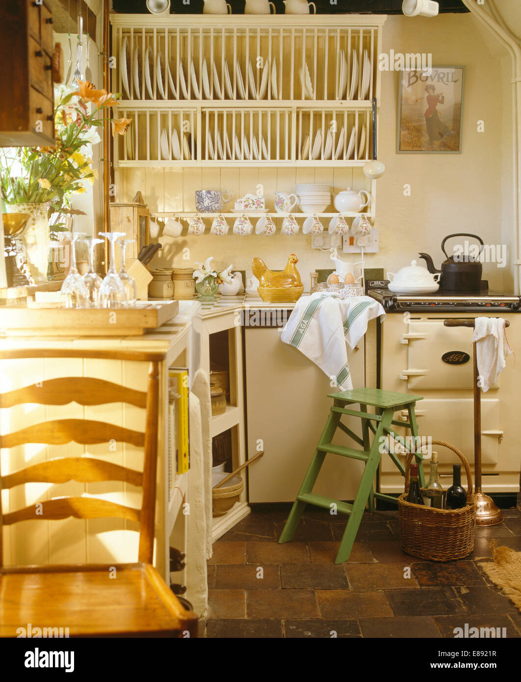 Plate rack on wall beside cream Aga oven in cream cottage kitchen Stock ...