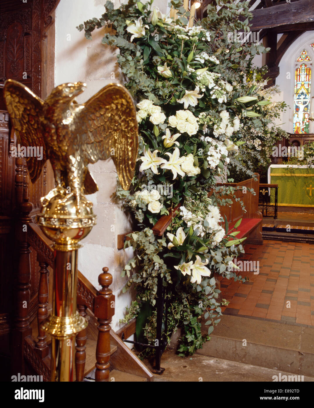 Gold eagle statue and white lilies in sumptuous floral arrangement for country church wedding Stock Photo