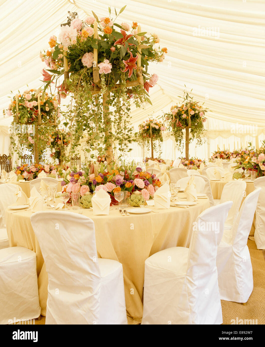 Pink roses in sumptuous floral arrangements on tables in marquee decorated for a summer wedding Stock Photo