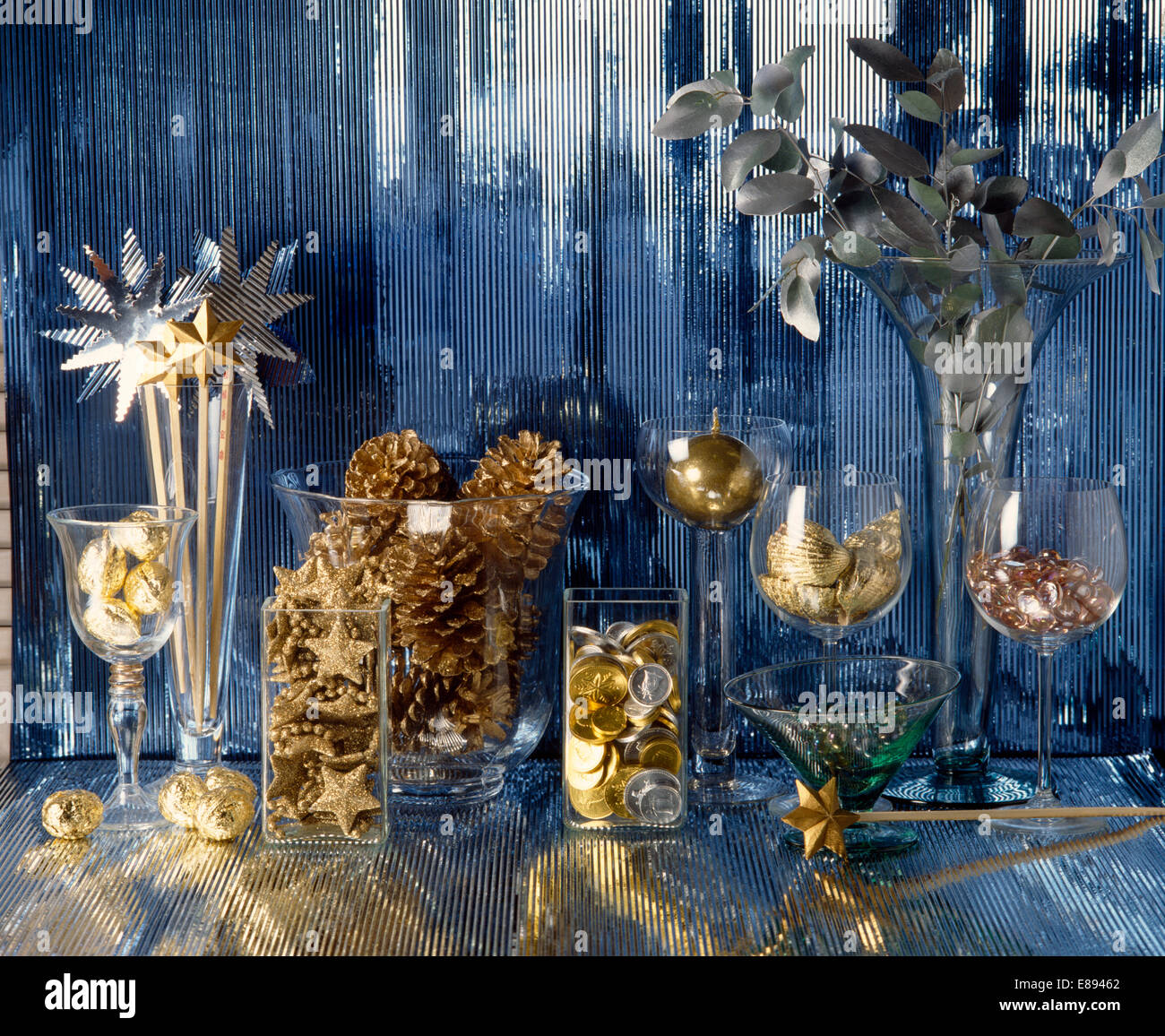 Still-Life of gold painted pine cones with gold coins in glass vases Stock Photo