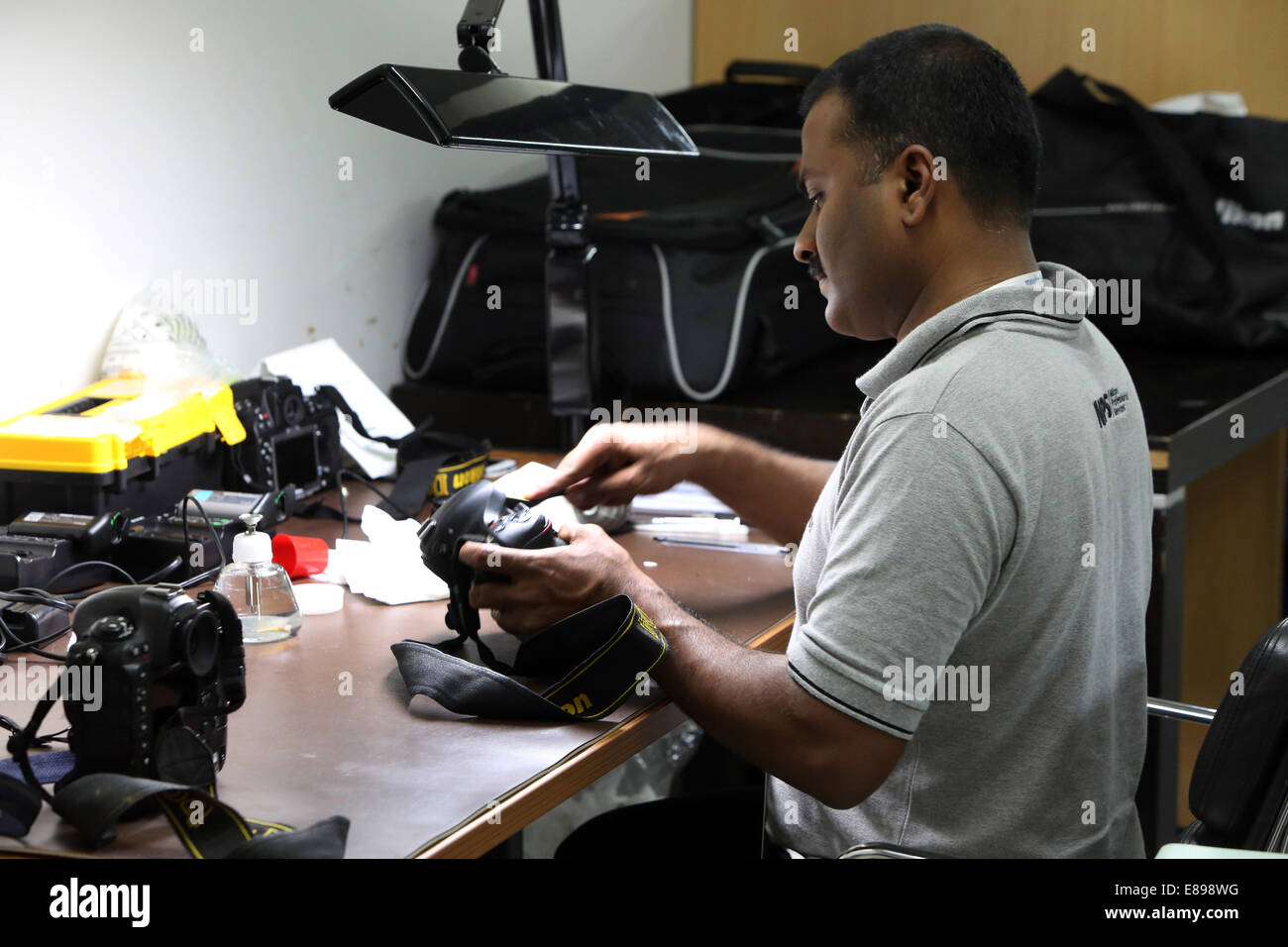 Dubai, United Arab Emirates, employees of Nikon Professional Service cleans an SLR Stock Photo