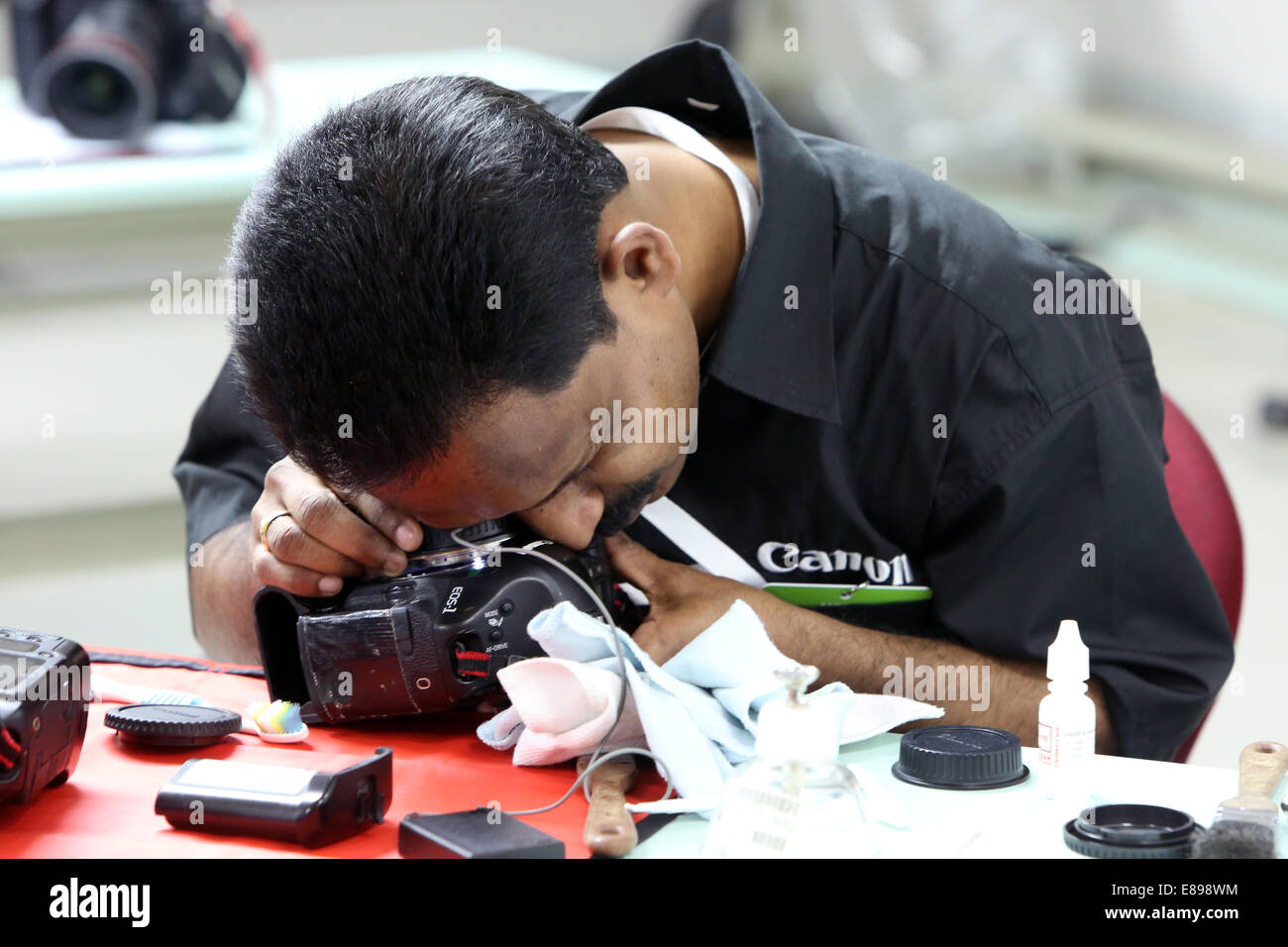 Dubai, United Arab Emirates, an employee of Canon Professional Service cleans an SLR Stock Photo
